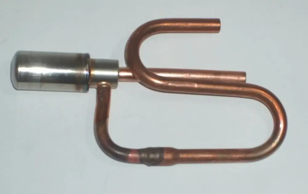 Daikin Ventilantrieb mit einer Kombination aus metallischen und kupfernen Komponenten, in einer gebogenen Form, auf einem neutralen Hintergrund.